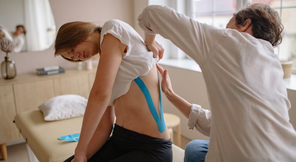 Massage therapist applying kinesiology tape for pain relief in Appleton clinic